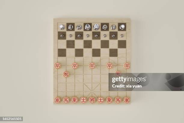 chinese chess and international chess pieces setup on chessboard - handelskrieg stock-fotos und bilder