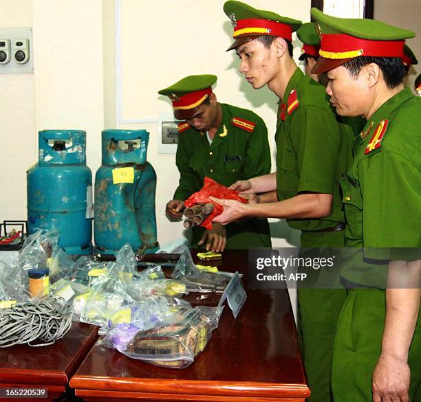 Policemen inspect items including two cooking gaz tubes which were reportedly used to make home made bombs by fish farmer Doan Van Vuon and his...