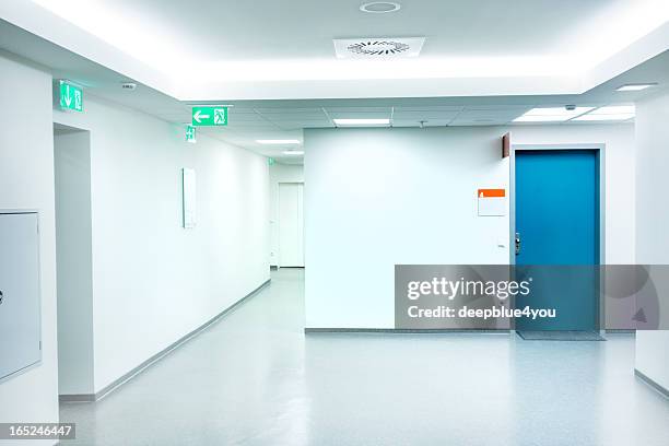 leere weiße krankenhaus-korridor mit blue door - notausgang stock-fotos und bilder