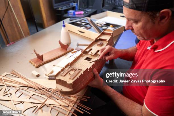 middle aged man assembling a model of an old ship in the garage at home - model kit fotografías e imágenes de stock