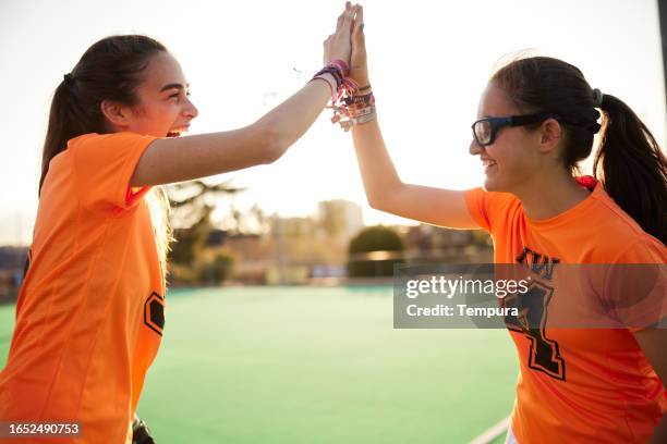sunlit triumph: two teammates celebrate victory with a high-five - youth sports competition stock pictures, royalty-free photos & images