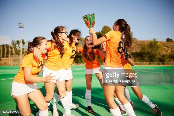 champions' joy: teammates elevate trophy in victory - teen awards stock pictures, royalty-free photos & images