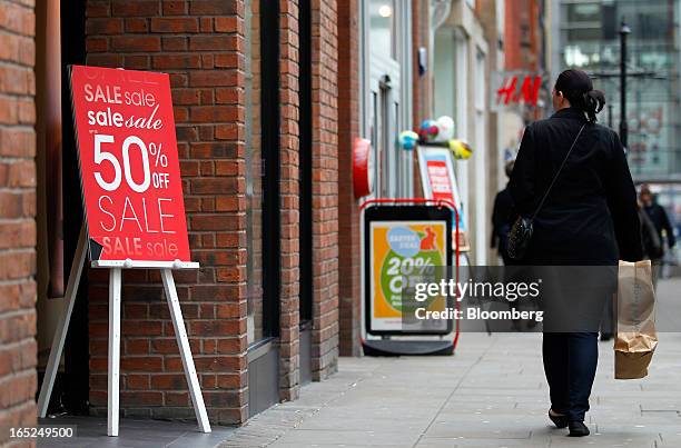 Pedestrian carries a shopping bag past a sign advertising a sale outside a Miss Selfridge fashion store in Manchester, U.K., on Monday, April 1,...