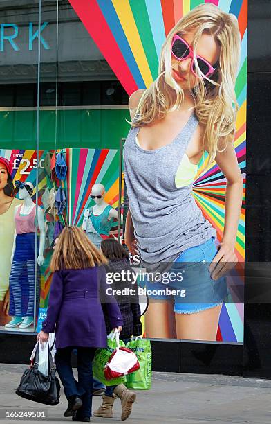 Pedestrians carry shopping bags past a window display at a Primark fashion store in Manchester, U.K., on Monday, April 1, 2013. U.K. Retail sales...