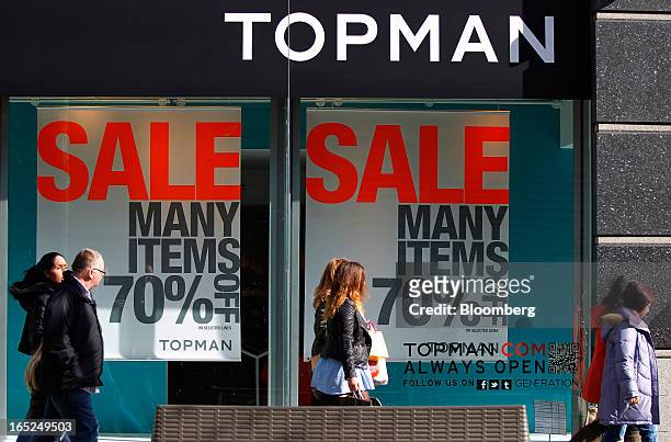 Pedestrians pass sales advertisements in the windows of a Topman fashion store, operated by Arcadia Group Ltd., in Manchester, U.K., on Monday, April...