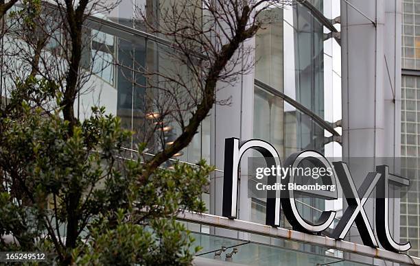 Logo stands above the entrance to a Next Plc store in Manchester, U.K., on Monday, April 1, 2013. U.K. Retail sales unexpectedly stagnated in March...