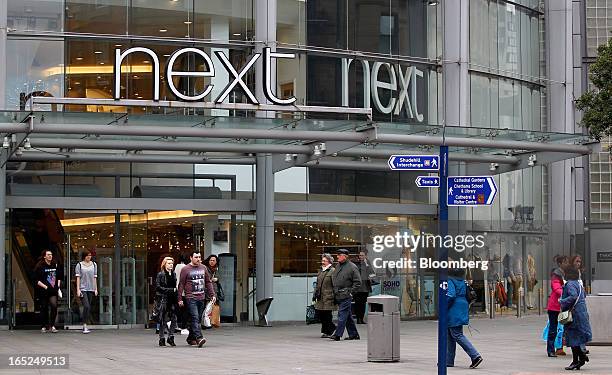 Pedestrians pass the entrance to a Next Plc store in Manchester, U.K., on Monday, April 1, 2013. U.K. Retail sales unexpectedly stagnated in March in...