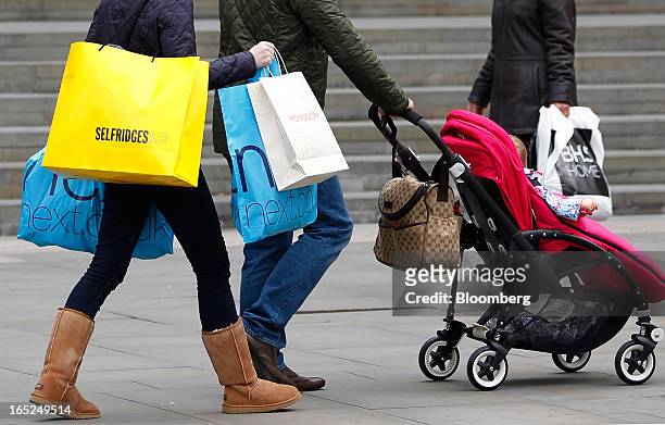 Pedestrian carries Selfridges & Co. And Next Plc-branded shopping bags along a street in Manchester, U.K., on Monday, April 1, 2013. U.K. Retail...