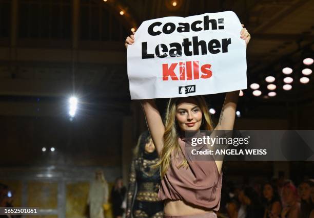 Peta protestor holds a sign reading "Coach: Leather Kills" as she demonstrates on the runway during the Coach Spring 2024 show during New York...