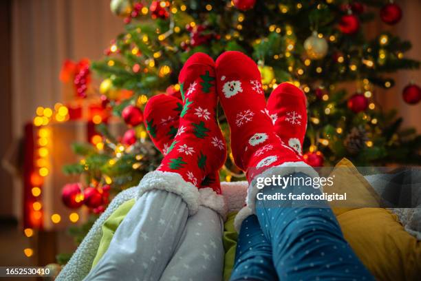 feet wearing red woolen christmas socks next to christmas tree - feet up stock pictures, royalty-free photos & images
