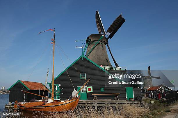 Wooden boat lies stands next to still-functioning windmills at the Zaanse Schans outdoor mueseum on April 1, 2013 in Zaandijk, Netherlands. Zaanse...