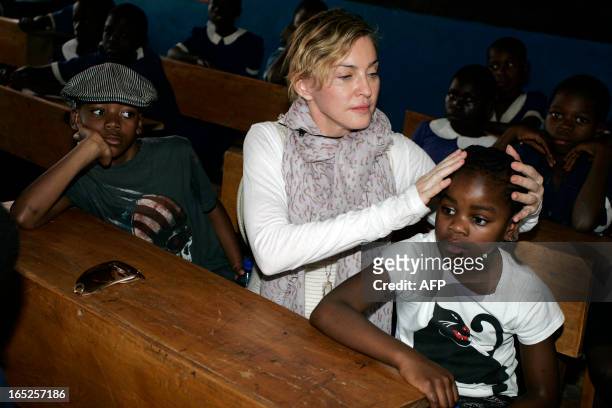 American pop star Madonna sits on April 2, 2013 with the two children she adopted in Malawi, David Banda and Mercy James , in a classroom of the...