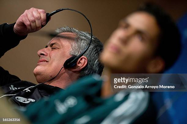 Head coach Jose Mourinho takes off his headphones annoyed while Real Madrid player Raphael Varane listen to questions from the media during a press...