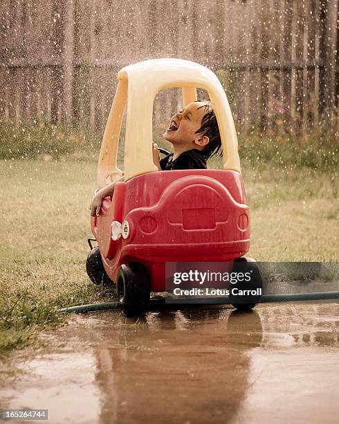 little boy laughing in play car - speelgoedauto stockfoto's en -beelden