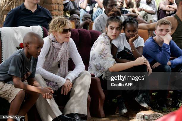 Pop Star Madonna sits with her biological and adopted children David Banda, Lourdes, Mercy James, and Rocco at Mkoko Primary School, one of the...