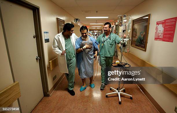 Cardiac surgeon Dr. Subdoh Verma and Registered Nurse Bradley Hill help patient Ashok Verma on his first walk following his surgery - 3 days after...