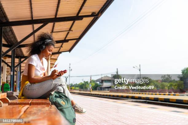 viajera africana esperando el tren en la estación de ferrocarril local. - inexpensive fotografías e imágenes de stock