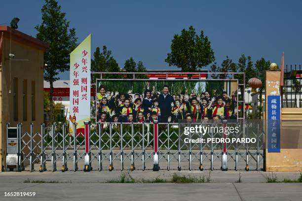 This picture taken on July 15, 2023 shows a poster featuring China's President Xi Jinping at the entrance to an industrial park in Konasheher county,...