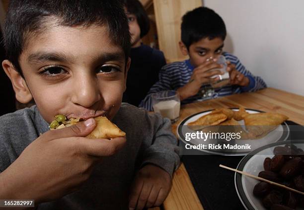 Four-year-old Ziyaad Khan bites into a samosa, one of the traditional foods Muslims break the daily fast with. His brother Muaaz is seen in the...