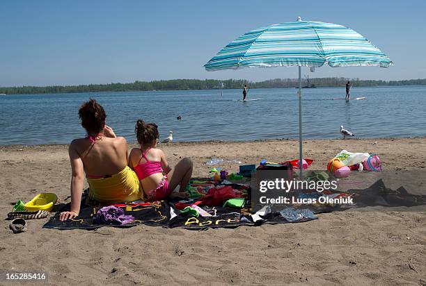 Paddle boarders passed by on Lake Ontario as Sofia Martins and her 5-year-old daughter Vanessa sat on Cherry beach eating cherries and feeding birds....