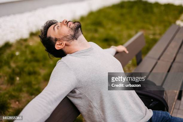 mann entspannt sich auf der stadtbank - bank müde frühling stock-fotos und bilder