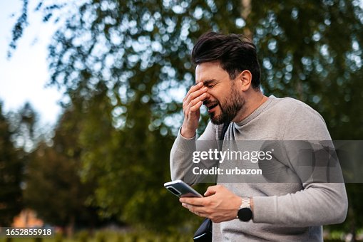 Man Sneezing While Using Smartphone Outdoors Man Sneezing While Using Smartphone Outdoors