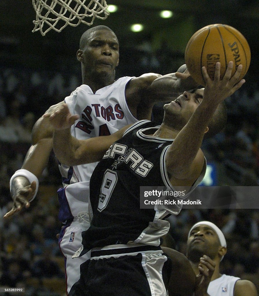 Raptors - 11/21/04 - TORONTO, ONTARIO - Chris Bosh defends against Tony Parker under the Raptors def