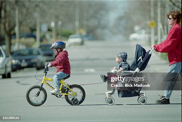 Alexander Mason powered by his bicycle pulls his little brother William, 14 months, with the help of a bungee cord as they head south on Mt. Pleasant...