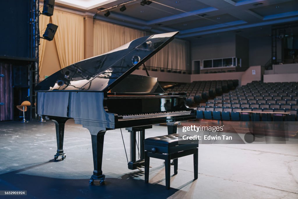 Grand piano on stage facing empty theatre auditorium