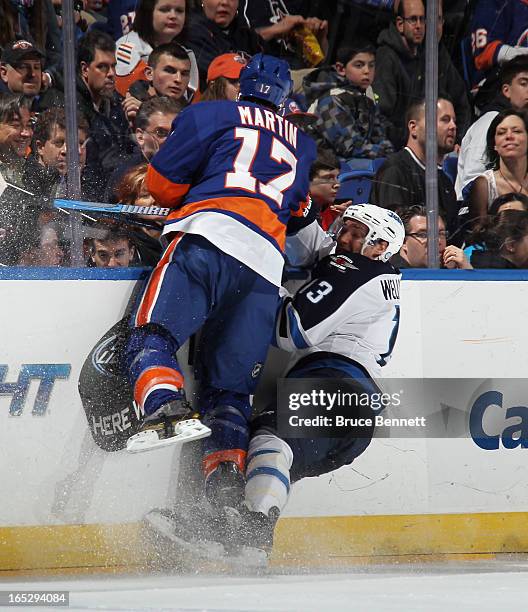 Matt Martin of the New York Islanders hits Kyle Wellwood of the Winnipeg Jets during the first period at the Nassau Veterans Memorial Coliseum on...
