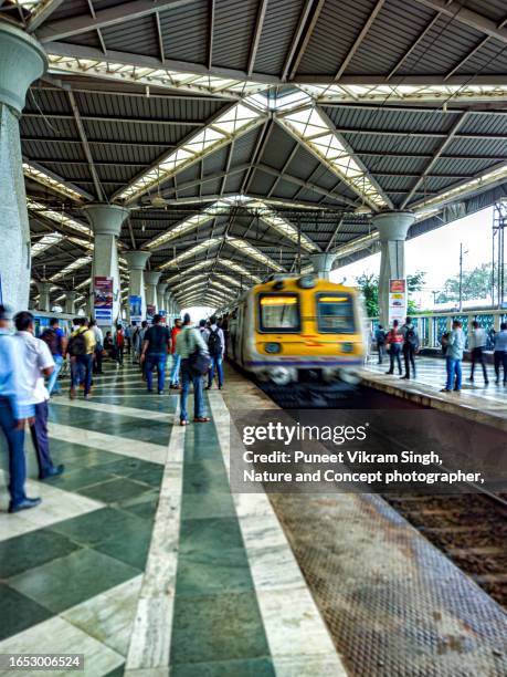 a local train arriving at the train station and mumbai's crowd , during morning rush hour. - mumbai railway station stock pictures, royalty-free photos & images