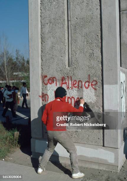 Protester paints anti-Pinochet graffiti on a wall near the Catholic University campus, Santiago, Chile, September 1985.