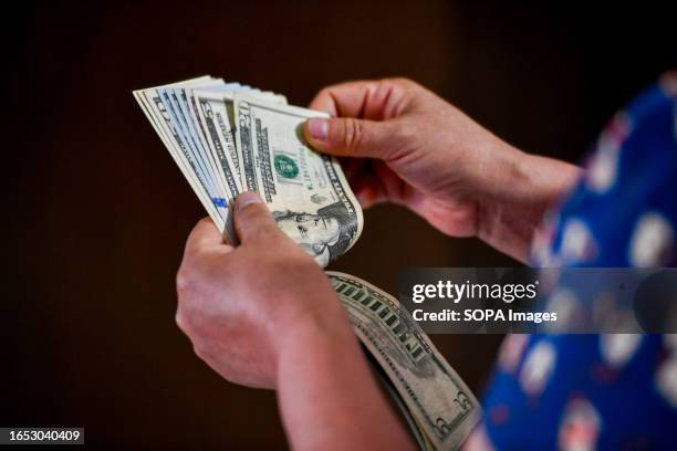 In this photo illustration, a person seen holding 5 and 20 US dollar bills in his hand.