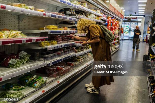 Lady chooses an item at a Sainsbury's supermarket. Sainsbury's is one of the largest UK retailers of groceries supermarkets founded in 1869.