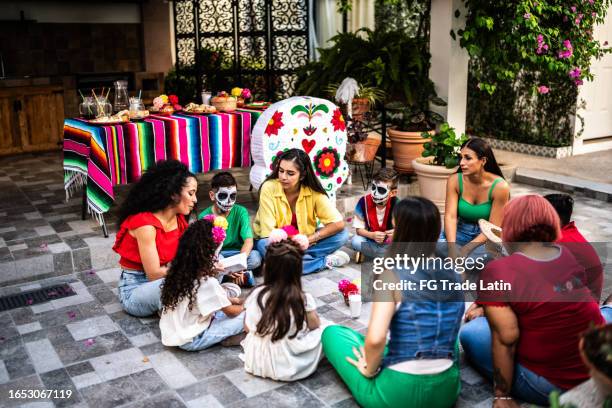 mother reading book to kids during a day of the death celebration - storyteller stock pictures, royalty-free photos & images
