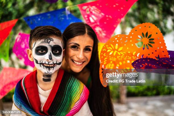 portrait of mother and son with sugar skull face paint during day of the dead celebration - dag-van-de-doden stockfoto's en -beelden