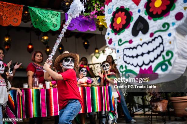 niño golpeando piñata durante un día de celebración de la muerte - dia-de-muertos fotografías e imágenes de stock