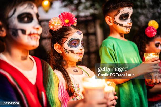 kids with sugar skull face paint holding candle during day of the dead celebration - candlelight ceremony stock pictures, royalty-free photos & images