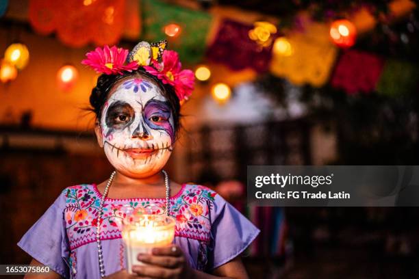 portrait of girl with sugar skull face paint holding candle during day of the dead celebration - la catrina stockfoto's en -beelden