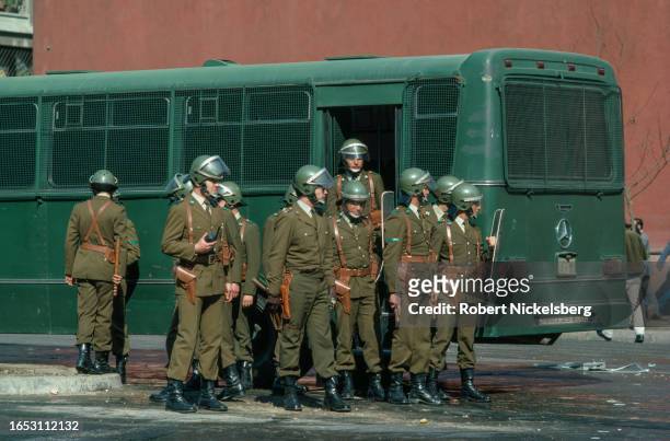 View of police officers in riot gear as they stand near a police transport in downtown Santiago, Chile, September 1985.