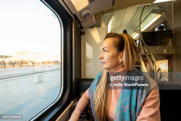 a woman looks out of the window - woman blond looking left window stockfoto's en -beelden