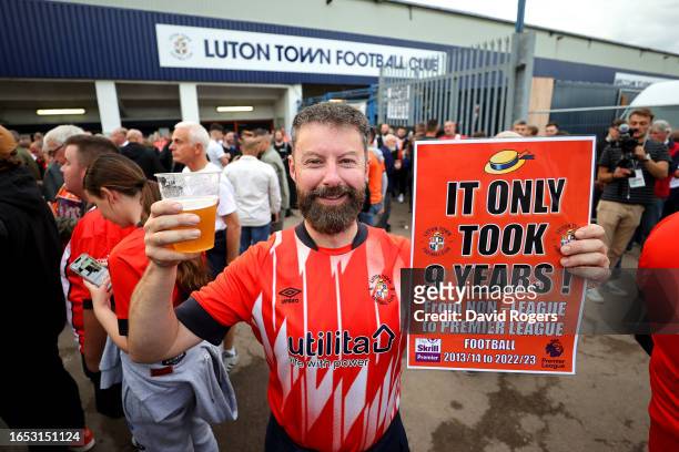Fan of Luton Town is seen with a drink and a sign reading 'It only took 9 years!' prior to the Premier League match between Luton Town and West Ham...