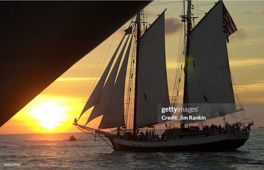 11/02 -- KEY WEST, FLA -- A sloop?, dwarfed by the hull of an snchored cruise ship, sails into the s
