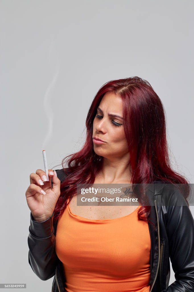 A young red-haired smoker looks suspiciously at her cigarette