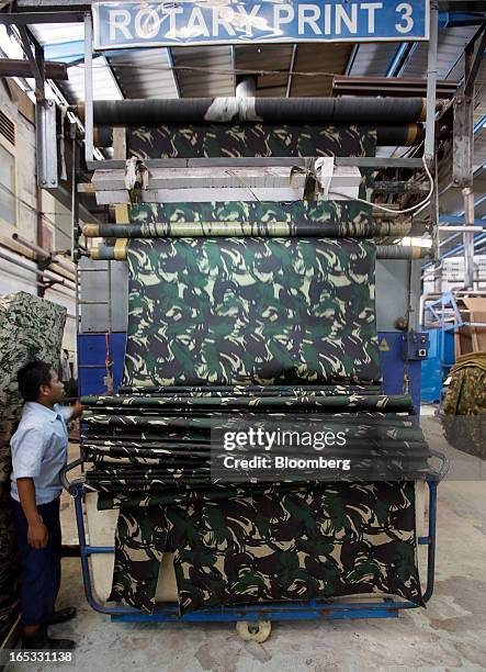 Worker monitors a roll of fabric as it comes out of a rotary printing machine in the printing area at a PT Sri Rejeki Isman factory in Sukoharjo,...