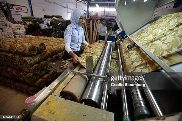 Worker inspects a roll of fabric in the printing area at a PT Sri Rejeki Isman factory in Sukoharjo, Java, Indonesia, on Wednesday, March 27, 2013....