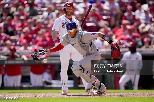 Miguel Amaya of the Chicago Cubs chases after a wild pitch past Jake Fraley of the Cincinnati Reds in the seventh inning during game one of a...