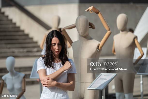 Performer showing pain surrounded by a multitude of mannequins placed during the World Physiotherapy Day to represent the diversity of ways in which...