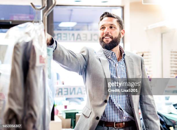 businessman in a small shop picking up his dry cleaning - dry cleaner 個照片及圖片檔