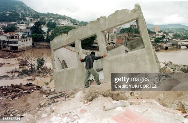 Man looks at the remains of the a building 11 November after Hurricane Mitch inundated the region and caused the Choulteca River to burst its banks...